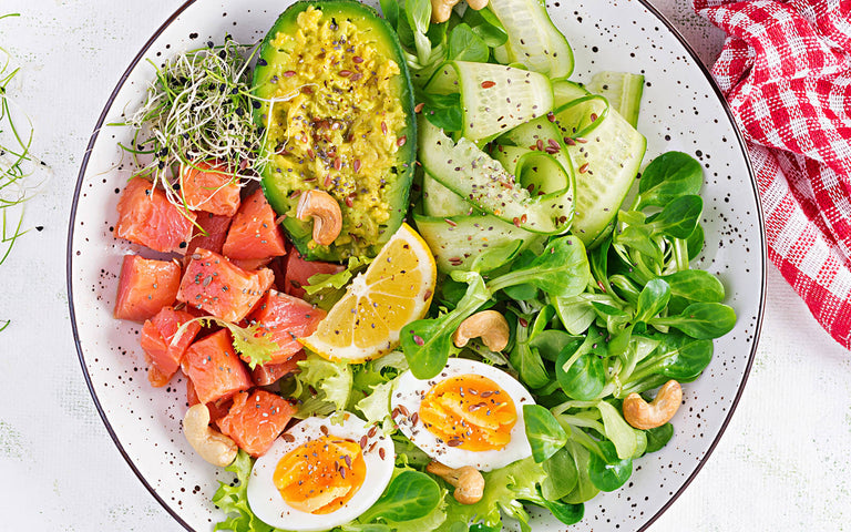 paleo vs keto: Salad with vegetables, eggs, nuts and salmon in a bowl