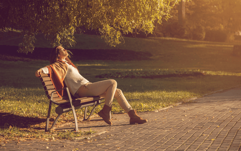 Lady in sunshine on park bench