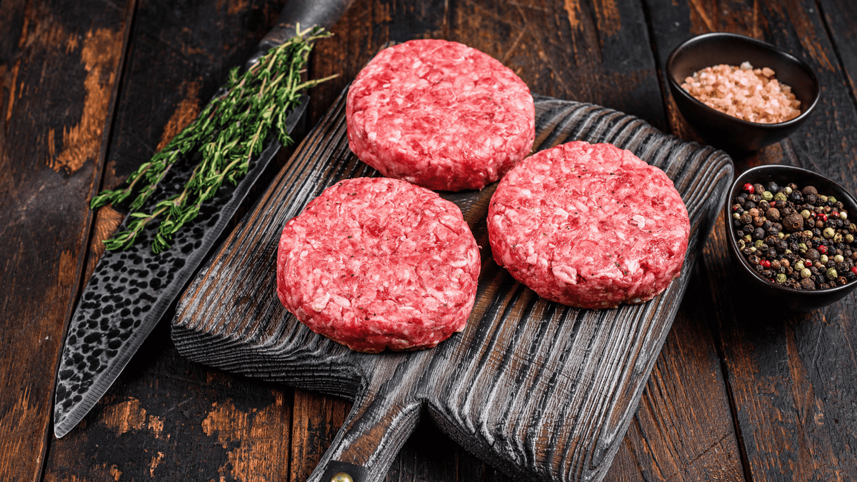 burger patties on board with knife salt and pepper