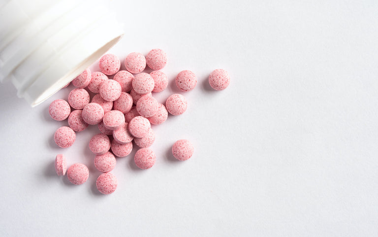 B12 tablets: Pink tablets spilling out of the bottle