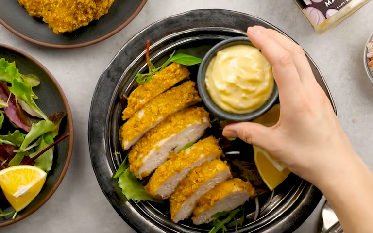 hand placing mayo on a plate with chicken