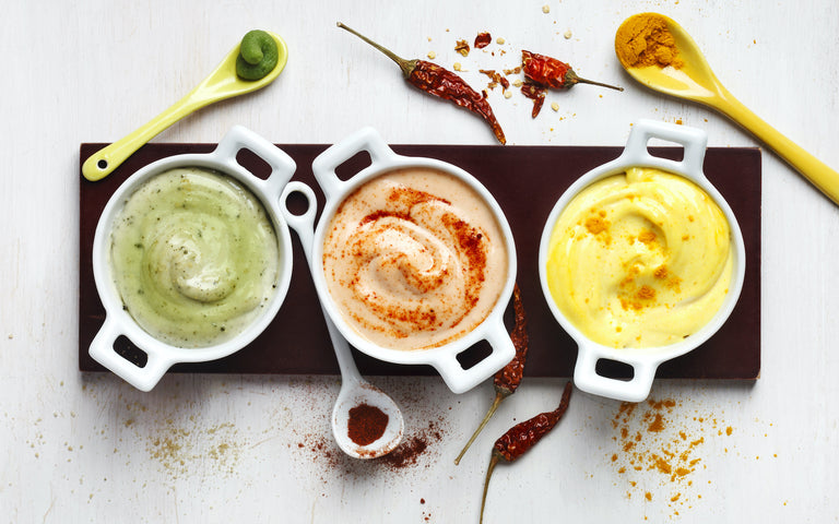 vegan mayonnaise: Mayonnaise in small white bowls with chilis, turmeric powder and wasabi in ceramic spoons