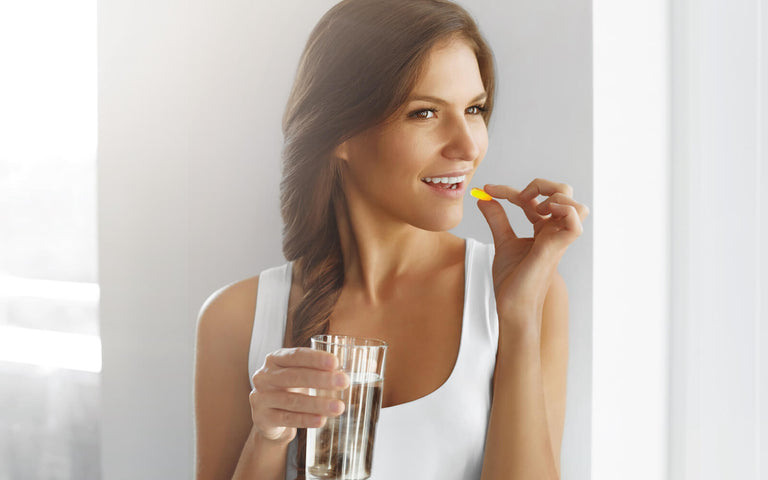 Do vitamins break a fast: woman about to drink a pill