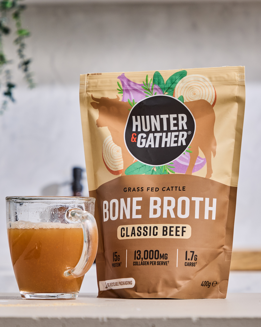 Hunter & Gather bone broth package with a glass of bone broth on a white surface.