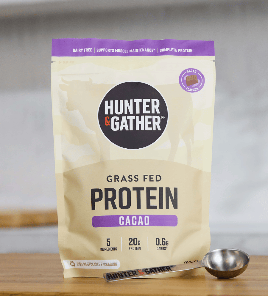 Hunter & Gather Grass Fed Protein Cacao package on a wooden surface with a spoon.