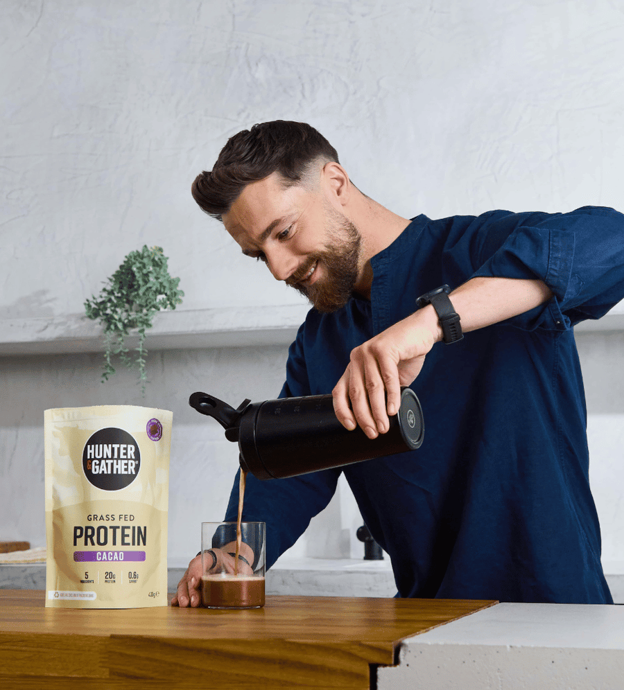 Man pouring a drink from a thermos into a glass next to a container of Hunter and Gather protein powder.