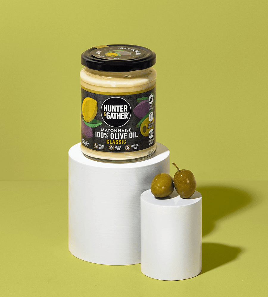 Jar of Hunter & Gather mayonnaise with olives on a green background
